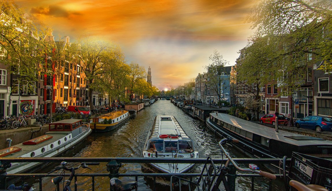 Tour boat sails under bridge in Amsterdam with beautiful cloudy sky