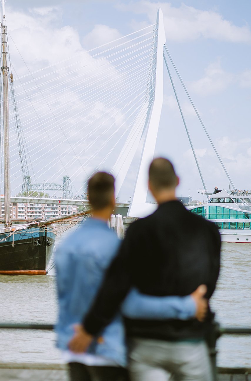 Couple looks arm in arm at the Erasmus Bridge