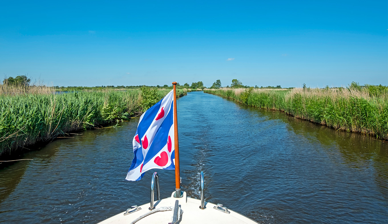 Boat with flag of Friesland sailing through the Alde Feanen National Park