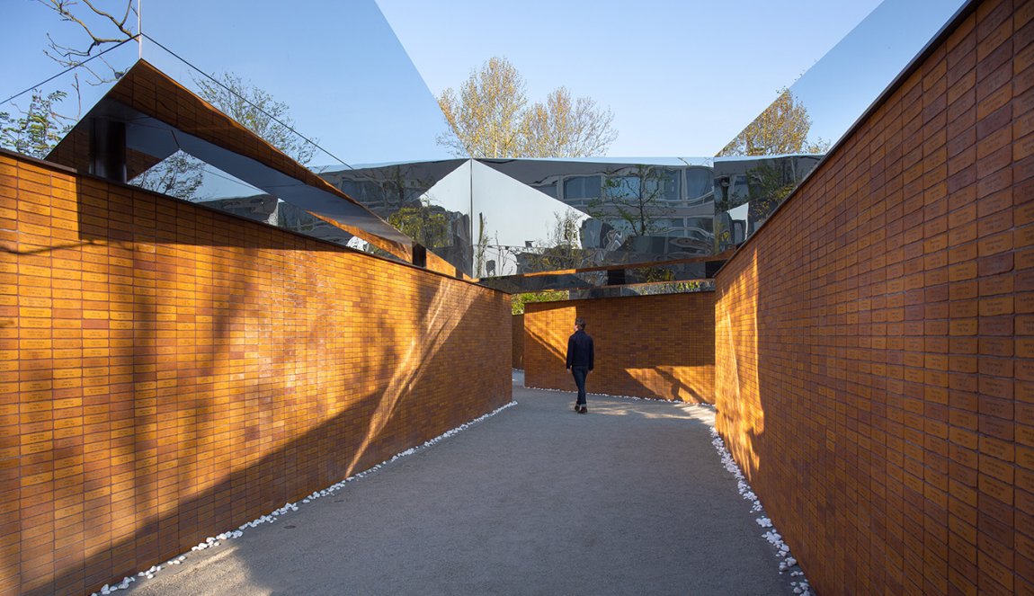 Visitor views walls full of names at Namenmonument Amsterdam